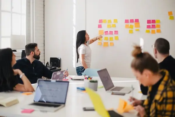 People working together in a room with sticky notes on the wall
