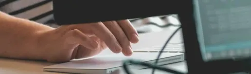 Person's hand on a track pad working at a computer